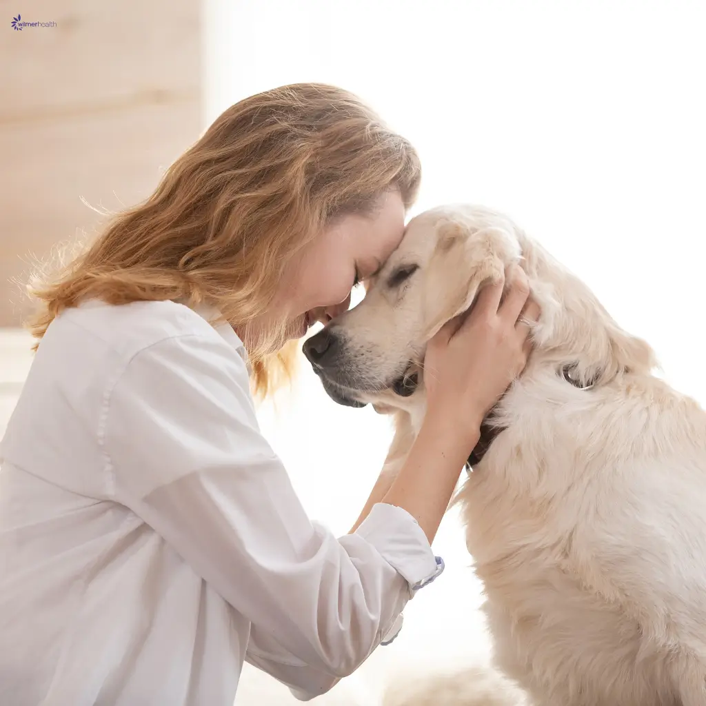 A woman cuddling her emotional support dog.