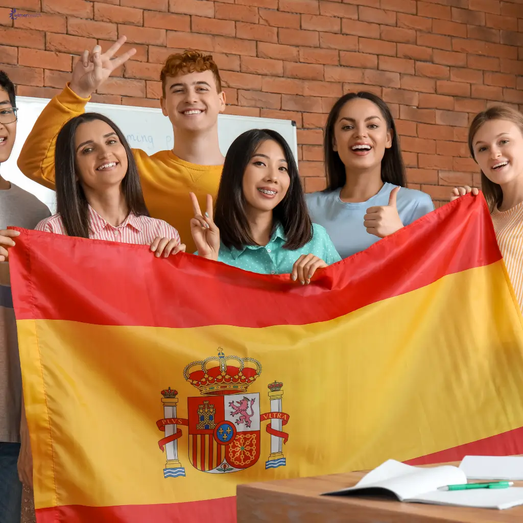 A group of students standing with the Spanish flag and smiling.