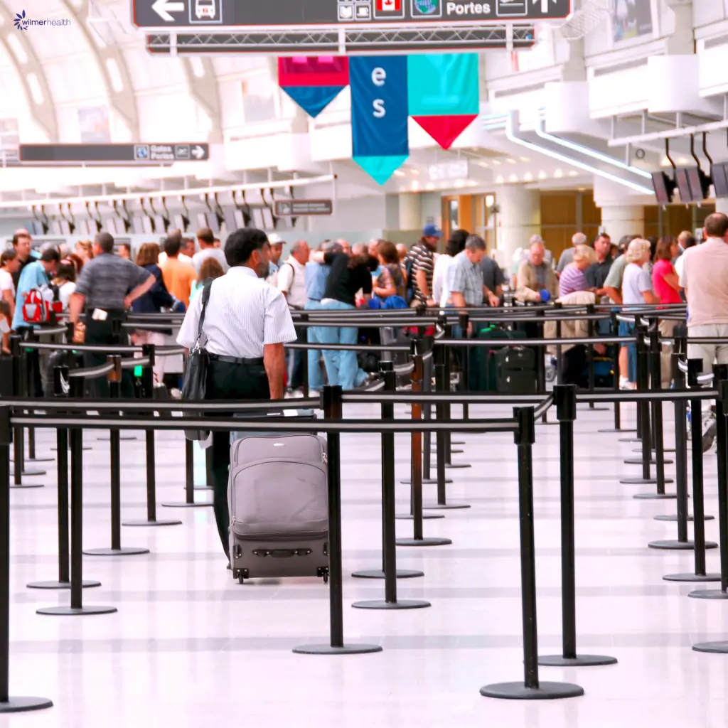 An image of a man queuing at an airport, preparing for travel with Wilmer Health's yellow fever vaccine exemption certificate.