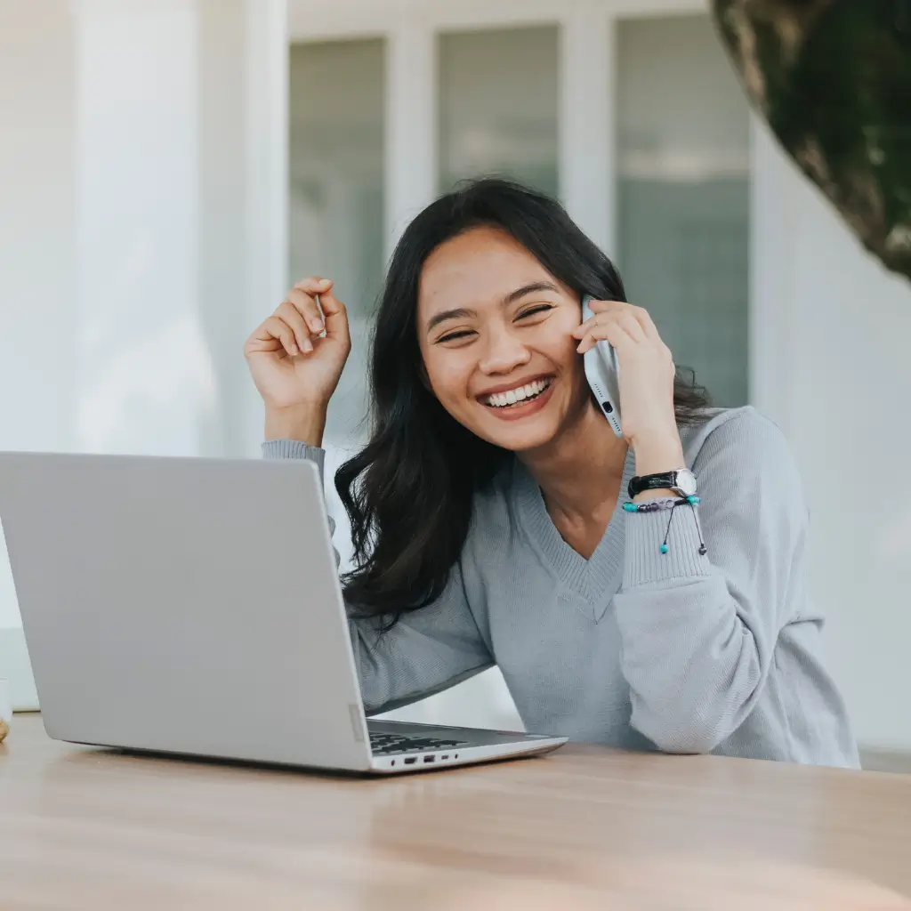 Smiling lady on her mobile phone and laptop.