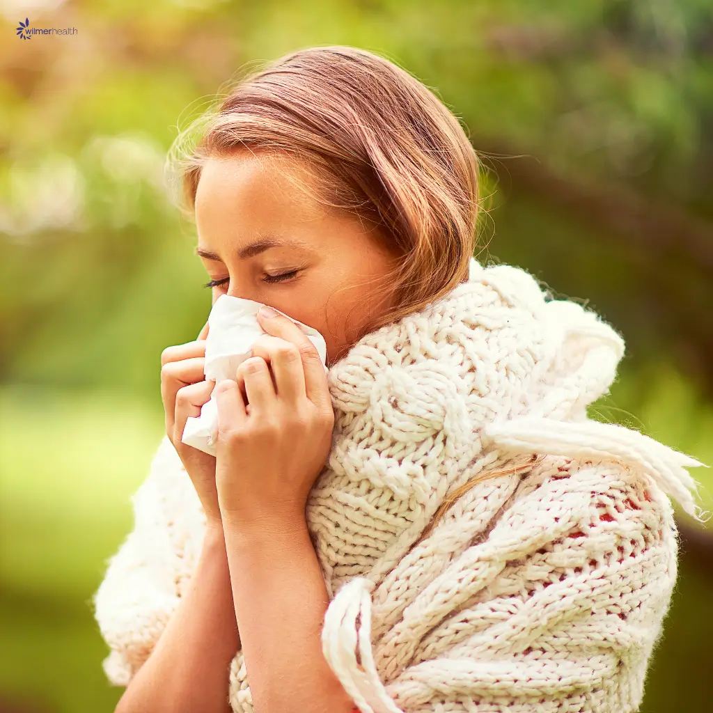 A lady with an allergy sneezing into a tissue.